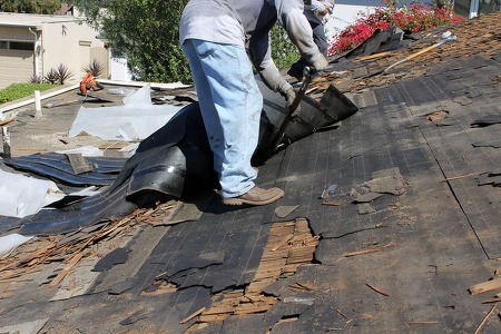 two roofing contractor removing tiles from a damaged roof