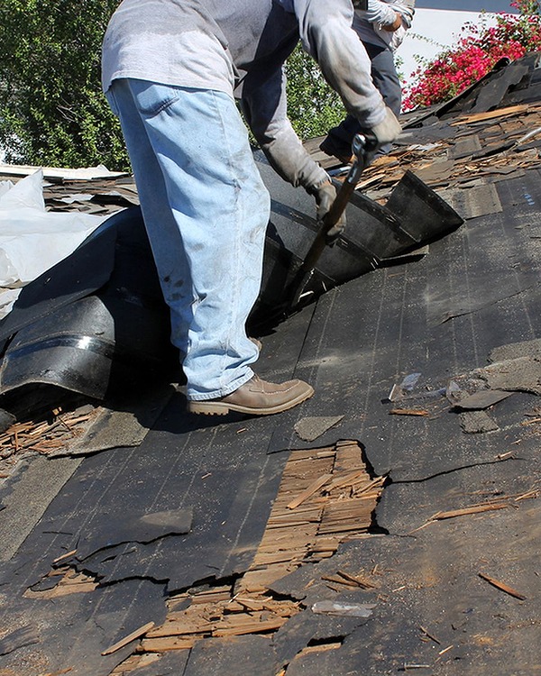 two roofing contractor removing tiles from a damaged roof
